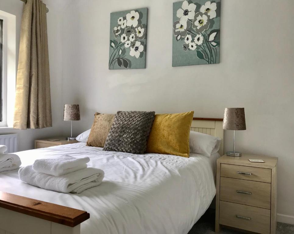 a bedroom with a white bed with pillows on it at The Woodfarm Lodge - 3 Bedroom House with free Parking in Oxford