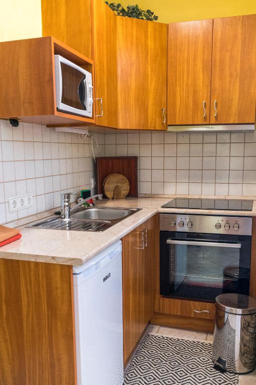 a kitchen with wooden cabinets and a sink and a microwave at Laubgassl in Mörbisch am See