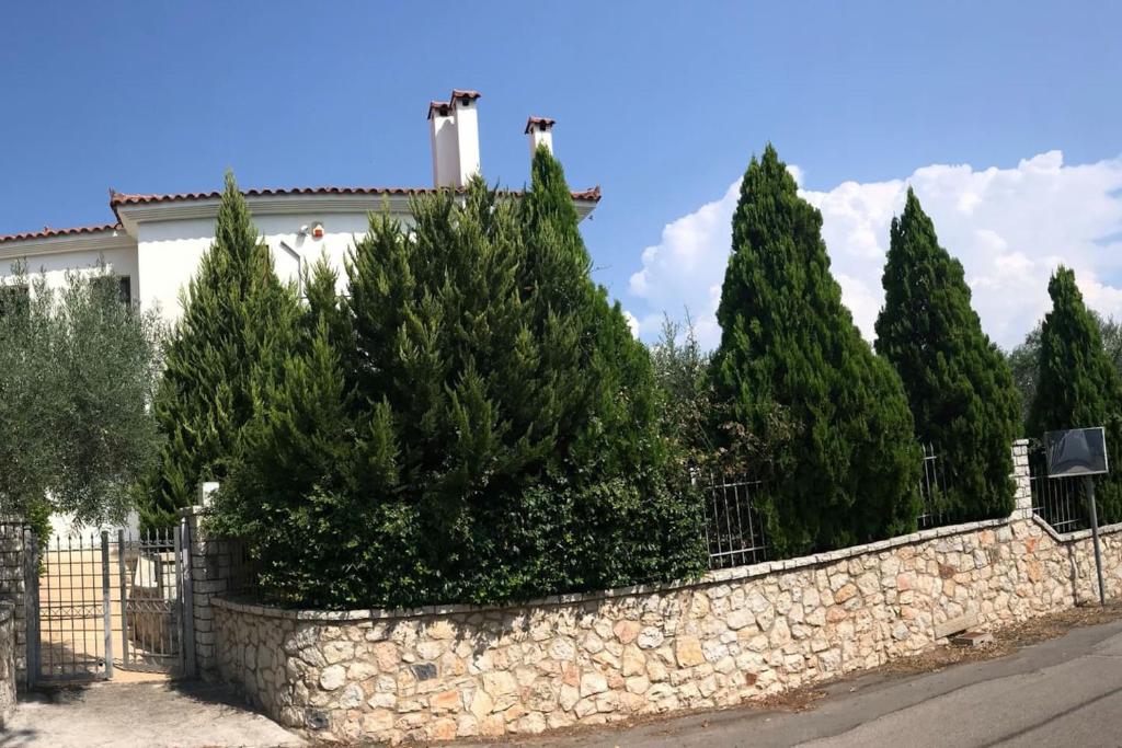 un mur en pierre avec des arbres devant un bâtiment dans l'établissement CASA DI MADI, à Chalcis