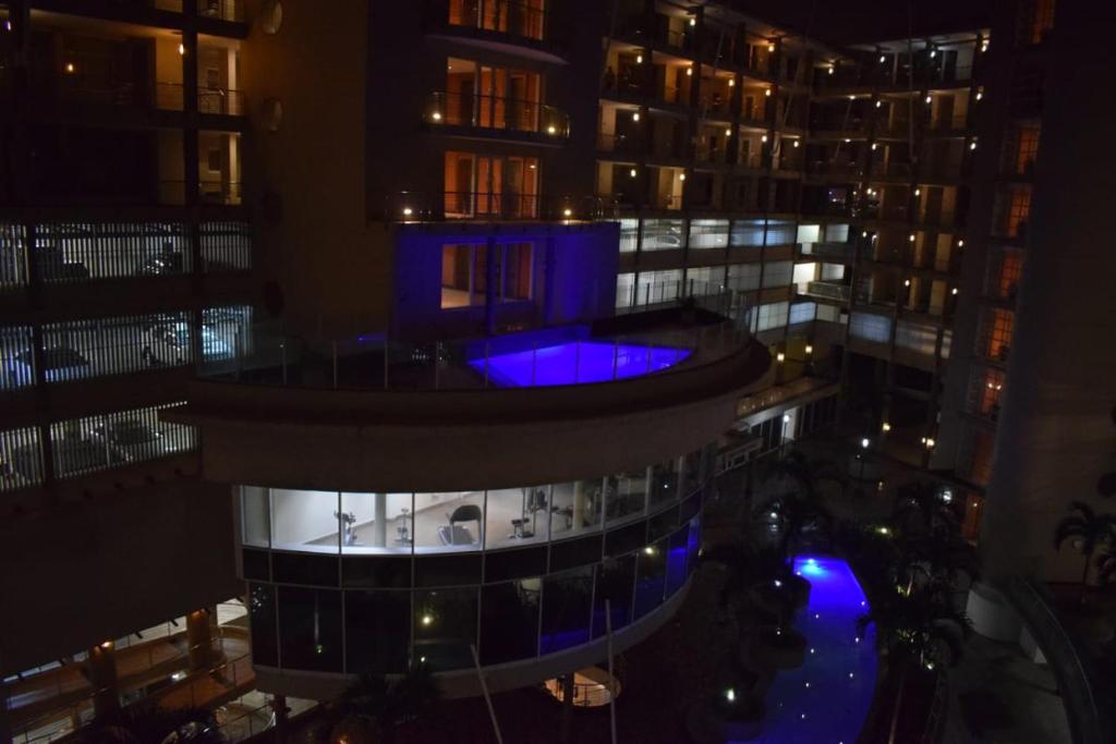 a view of a building at night with a blue pool at Two bedroom apartment at the Sails in Durban