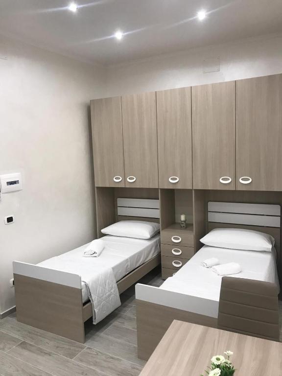 a bedroom with two beds and wooden cabinets at La Maison Doppia in Stornara
