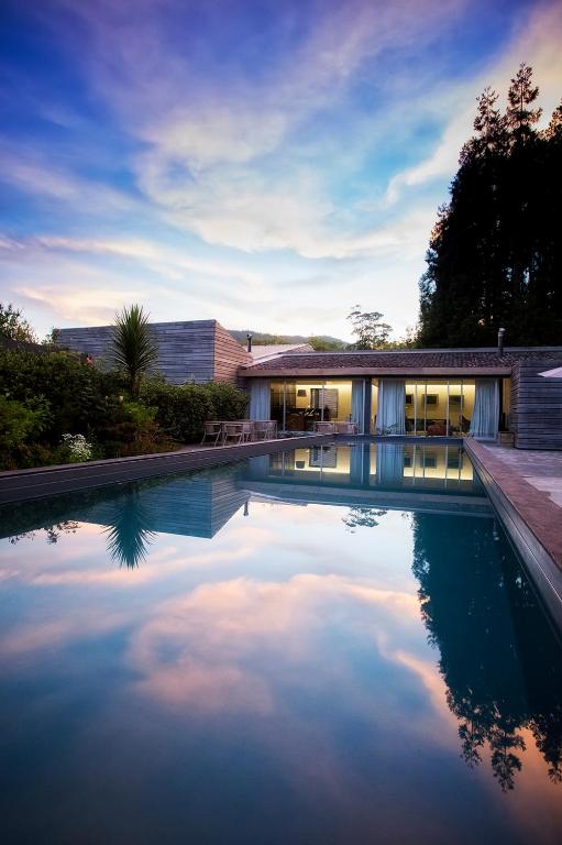 a swimming pool in front of a house at Furnas Lake Forest Living in Furnas
