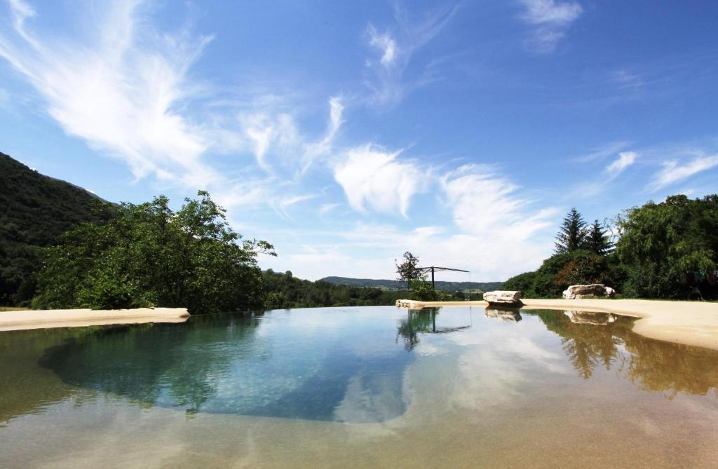 a large body of water with trees and a blue sky at Aporia in Hostun