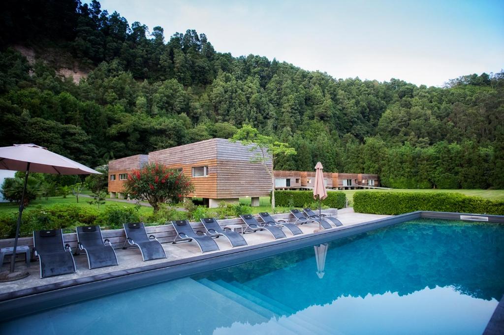 uma piscina com cadeiras e um guarda-sol e uma casa em Furnas Lake Forest Living nas Furnas