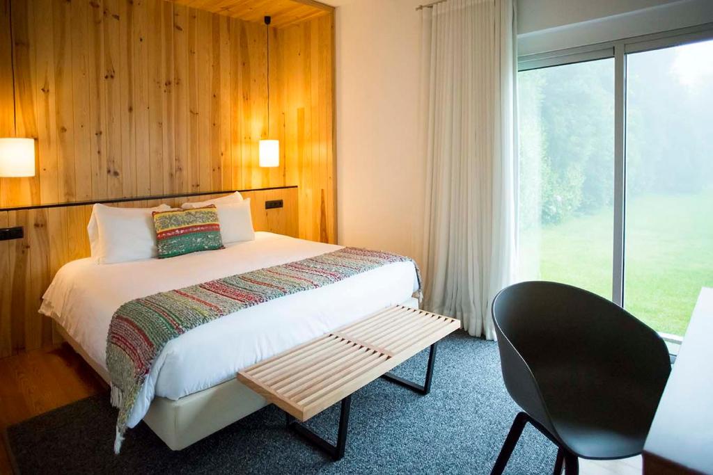 a bedroom with a bed and a chair and a window at Furnas Lake Forest Living in Furnas