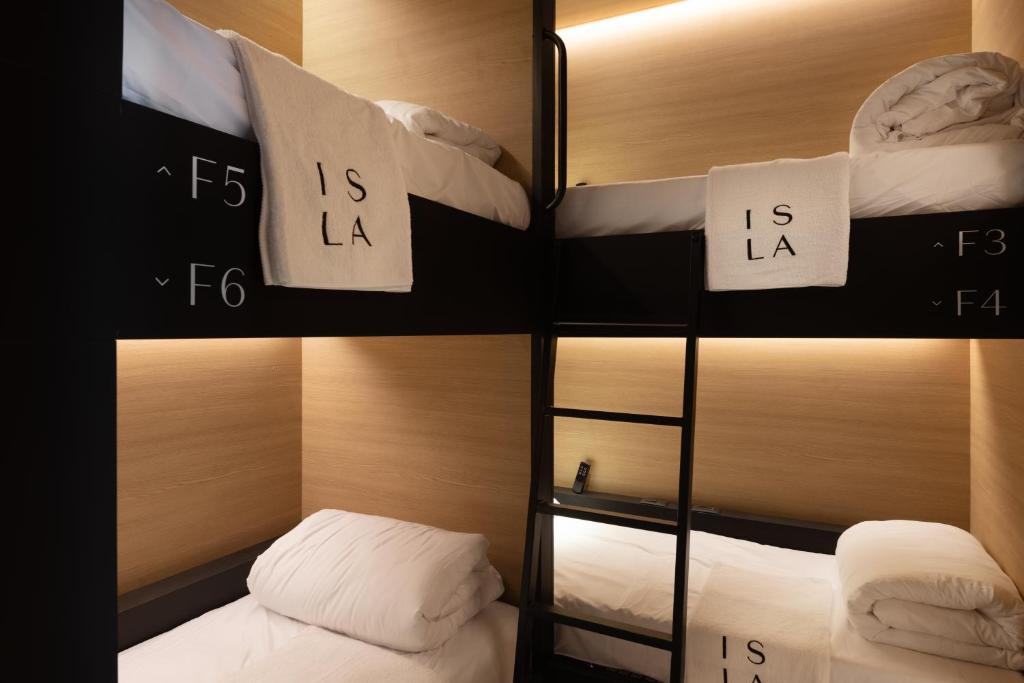 Habitación con 2 literas y almohadas blancas. en ISLA Tel Aviv en Tel Aviv