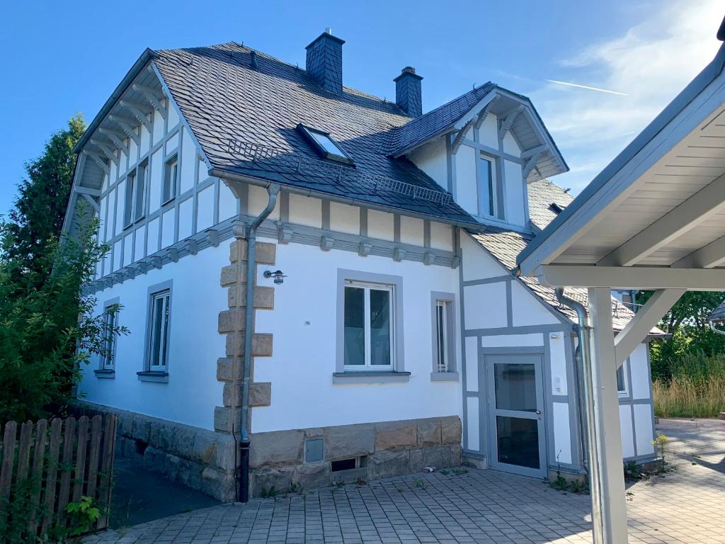 une maison blanche avec un toit en gambrel dans l'établissement WAGNERS Ferienwohnungen in Norhalben, à Nordhalben