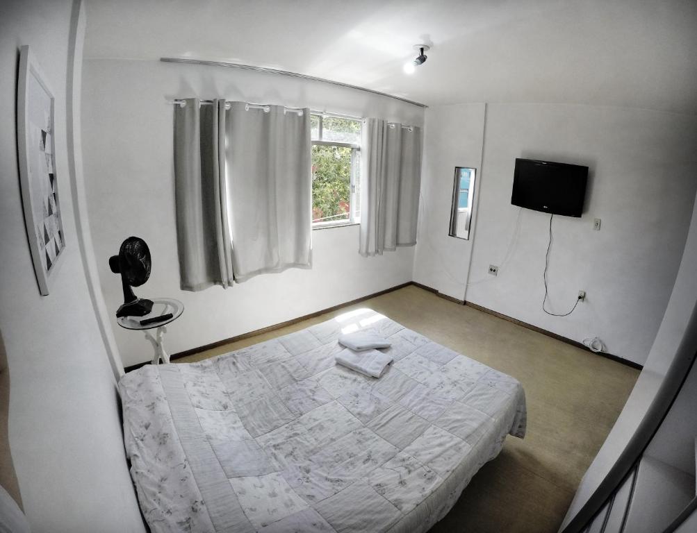 Cette chambre blanche comprend un lit et une télévision. dans l'établissement Apartamento no Centro de Friburgo, à Nova Friburgo
