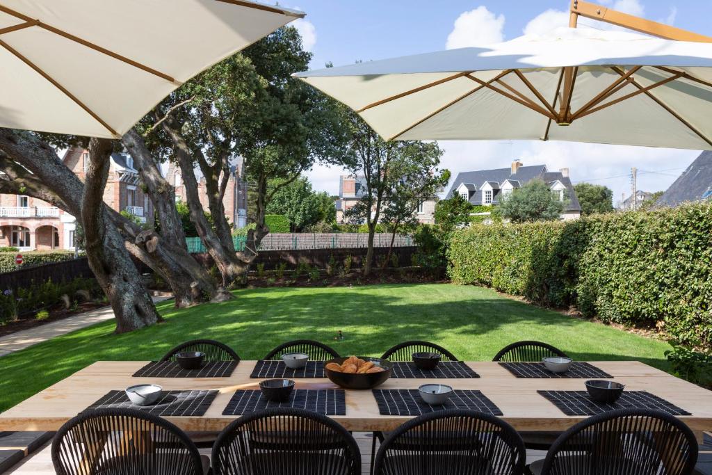 a wooden table with chairs and an umbrella at Entre Deux Mers by Cocoonr in Dinard