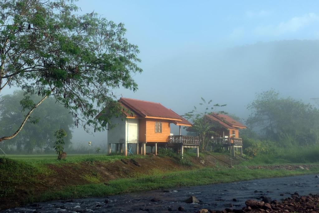 a couple of houses on a hill next to a river at ต้นน้ำน่าน บ่อเกลือ in Ban Sale