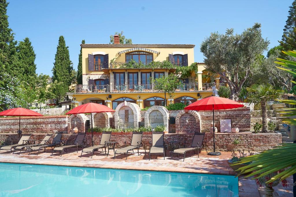 una casa con sillas y sombrillas junto a una piscina en Villa Taraça Alaçatı Romantik Otel, en Alacati