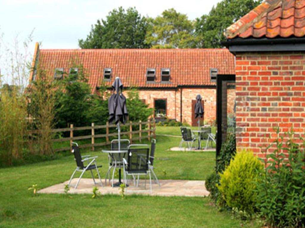 einen Garten mit Stühlen und Tischen sowie ein Backsteingebäude in der Unterkunft Annapurna Guest House in Lingwood