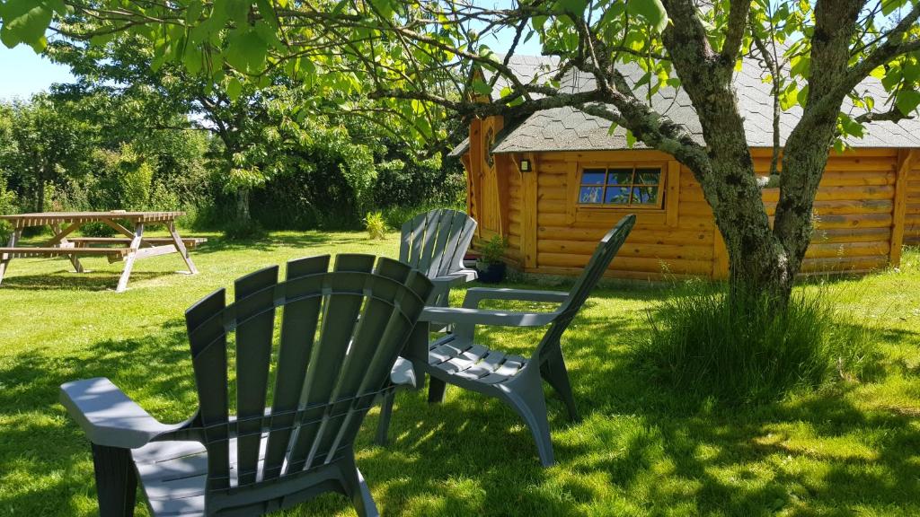 two chairs sitting in the grass in front of a cabin at La Bercéenne in Jupilles