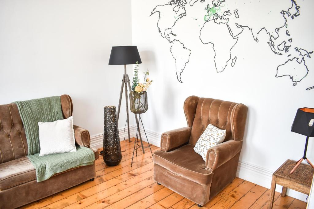 a living room with two chairs and a world map on the wall at A Casa da Cascata in Ribeira Grande