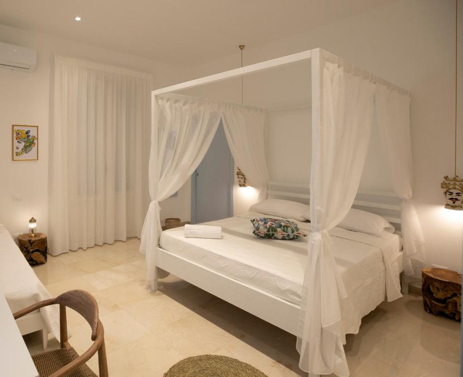 - une chambre avec un lit blanc à baldaquin dans l'établissement Cocciu d'amuri, à San Vito Lo Capo