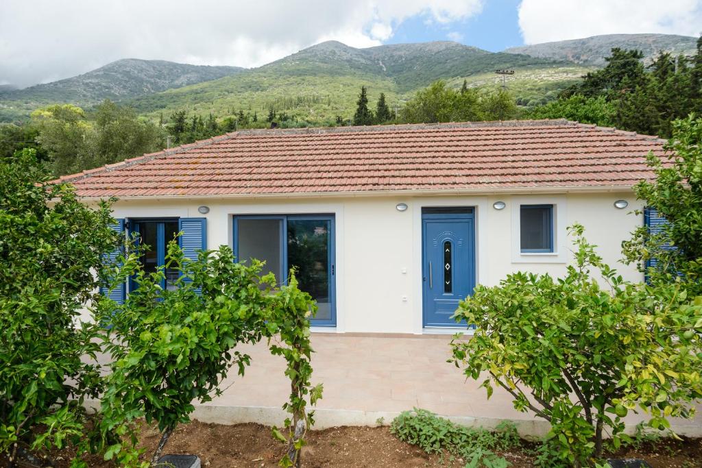 a house with blue doors and mountains in the background at Kokonis House in Ayia Evfimia