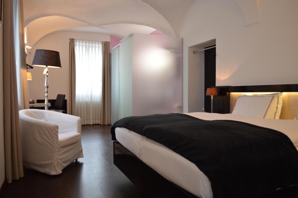 une chambre d'hôtel avec un lit et une chaise dans l'établissement Boutique Hotel La Rinascente, à Locarno