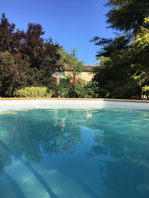 una piscina di acqua blu con alberi sullo sfondo di Moulin De Coupigny a Fontenille-Saint-Martin-d'Entraigues