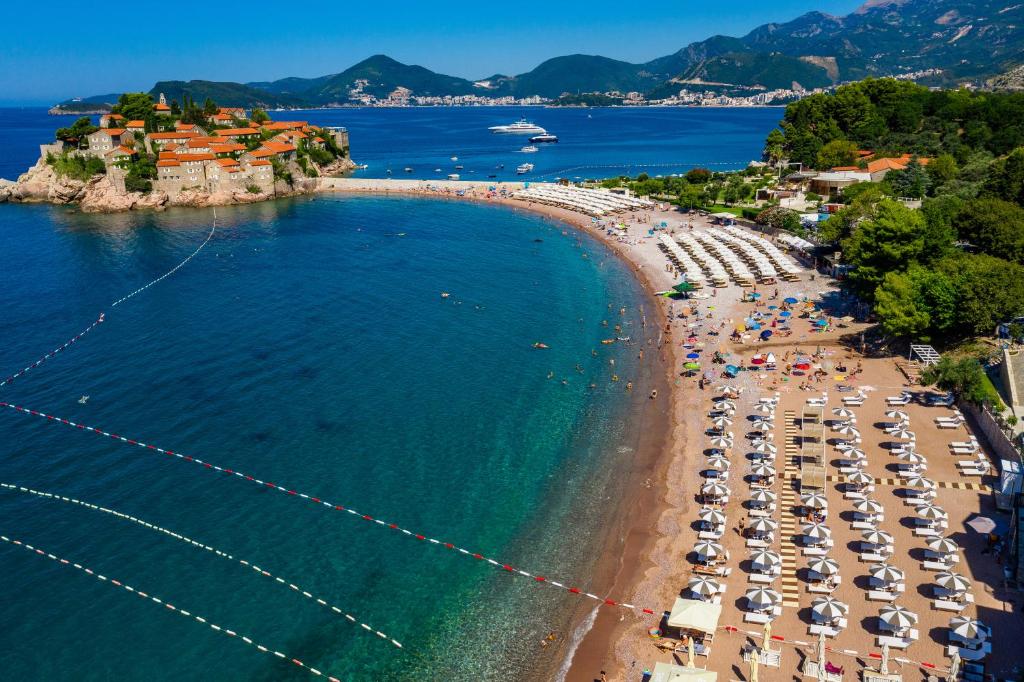 an aerial view of a beach with chairs and umbrellas at Hotel California by Aycon in Sveti Stefan