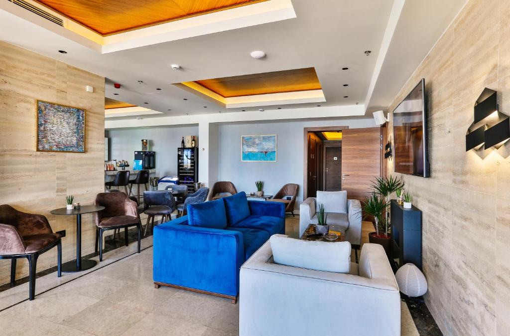 a lobby with blue couches and chairs and a bar at Hotel California by Aycon in Sveti Stefan
