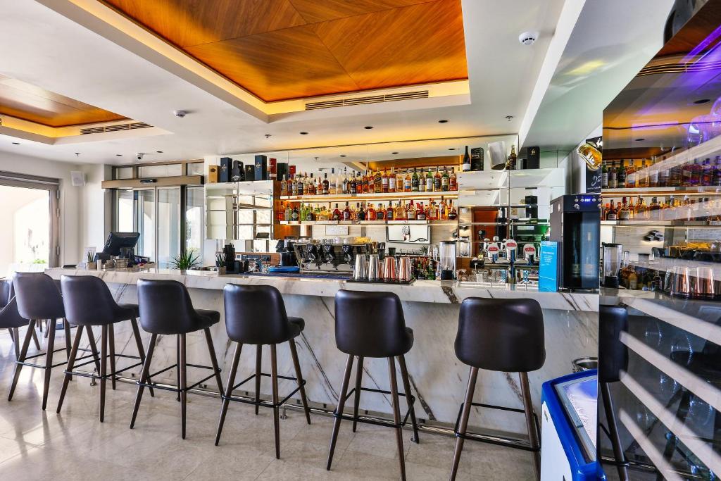 a bar with black stools in a room at Hotel California by Aycon in Sveti Stefan