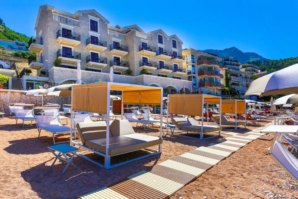 a group of chairs and umbrellas on a beach at Hotel California by Aycon in Sveti Stefan