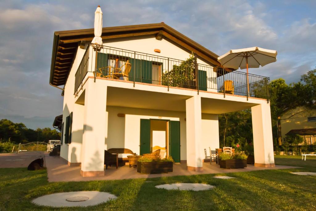 a white house with a balcony and an umbrella at Agriturismo Fiumi Uniti in Lido di Dante