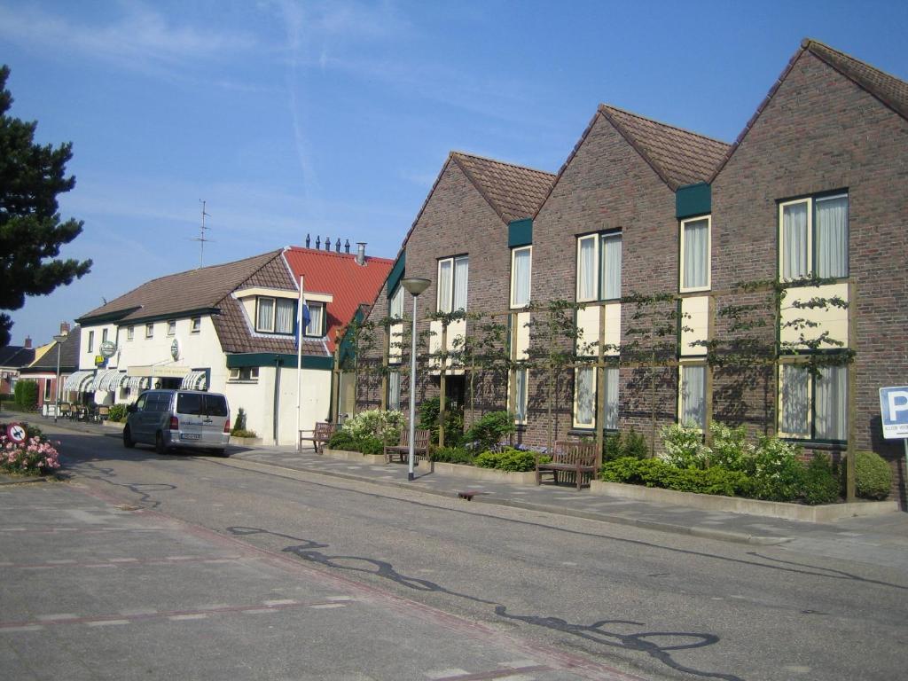 eine Reihe von Häusern auf einer Straße mit einem Auto in der Unterkunft Hotel Ekamper in Oosteinde