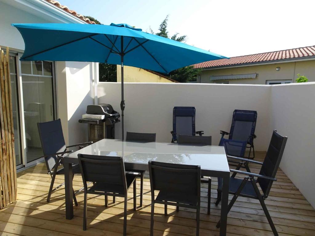 a table and chairs with a blue umbrella on a patio at Villa du Cabestan in Andernos-les-Bains