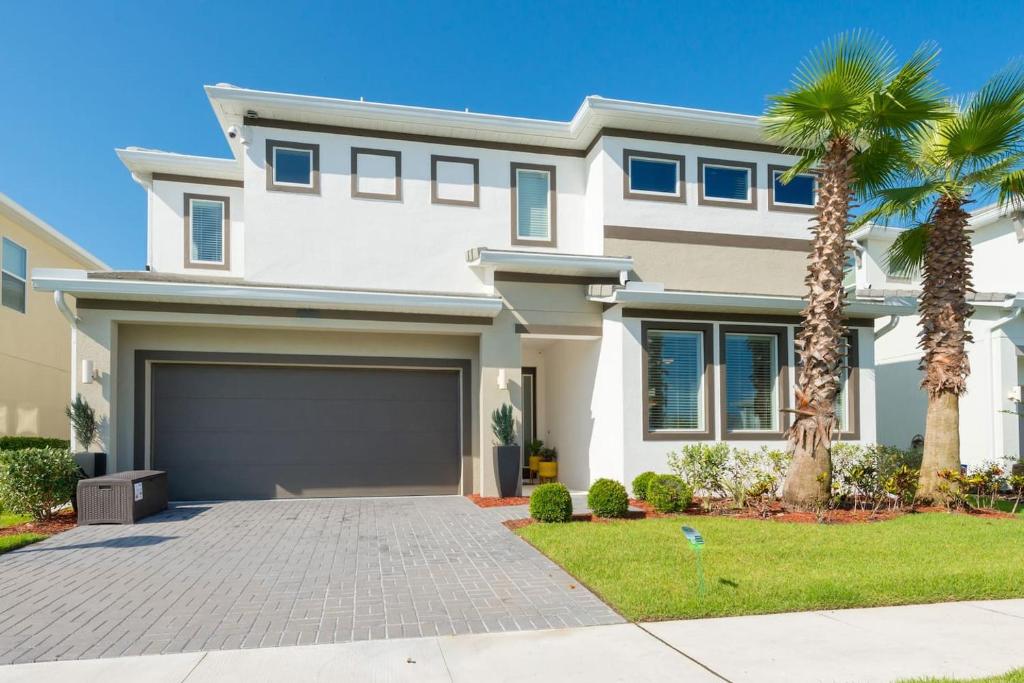 a house with palm trees in front of it at New Lovely Home at Sonoma Resort at Tapestry in Kissimmee