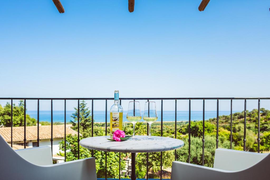 - une table avec une bouteille de vin et des fleurs sur le balcon dans l'établissement Hotel Rio Molas, à Muravera