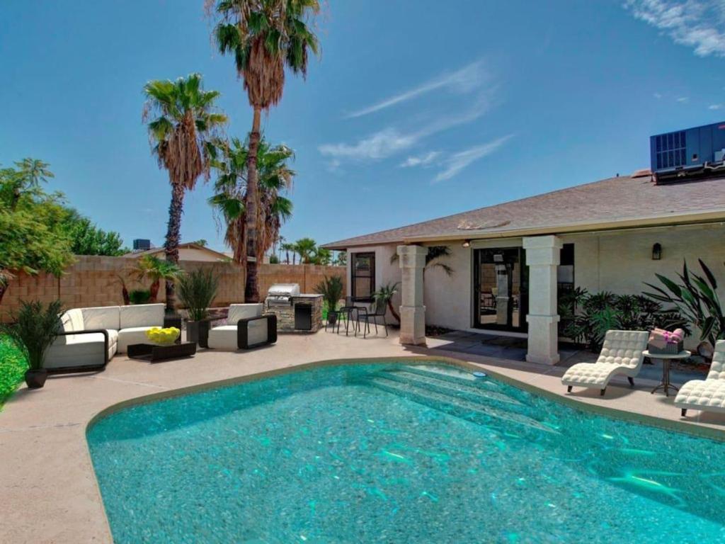 a swimming pool in front of a house with palm trees at Kierland Villa · North Scottsdale Home w/Pool~Walk to Kierland Area in Scottsdale