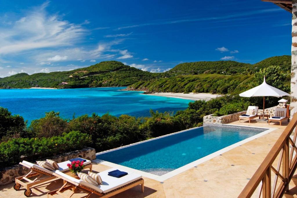 a villa with a swimming pool and a view of the ocean at Canouan Estate Resort & Villas in Canouan