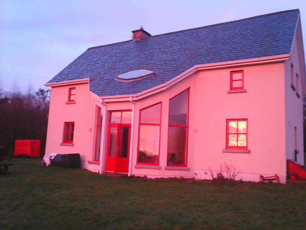 una casa rosa con tetto nero e ampie finestre di Harmony Hall Veganic a Kilkenny