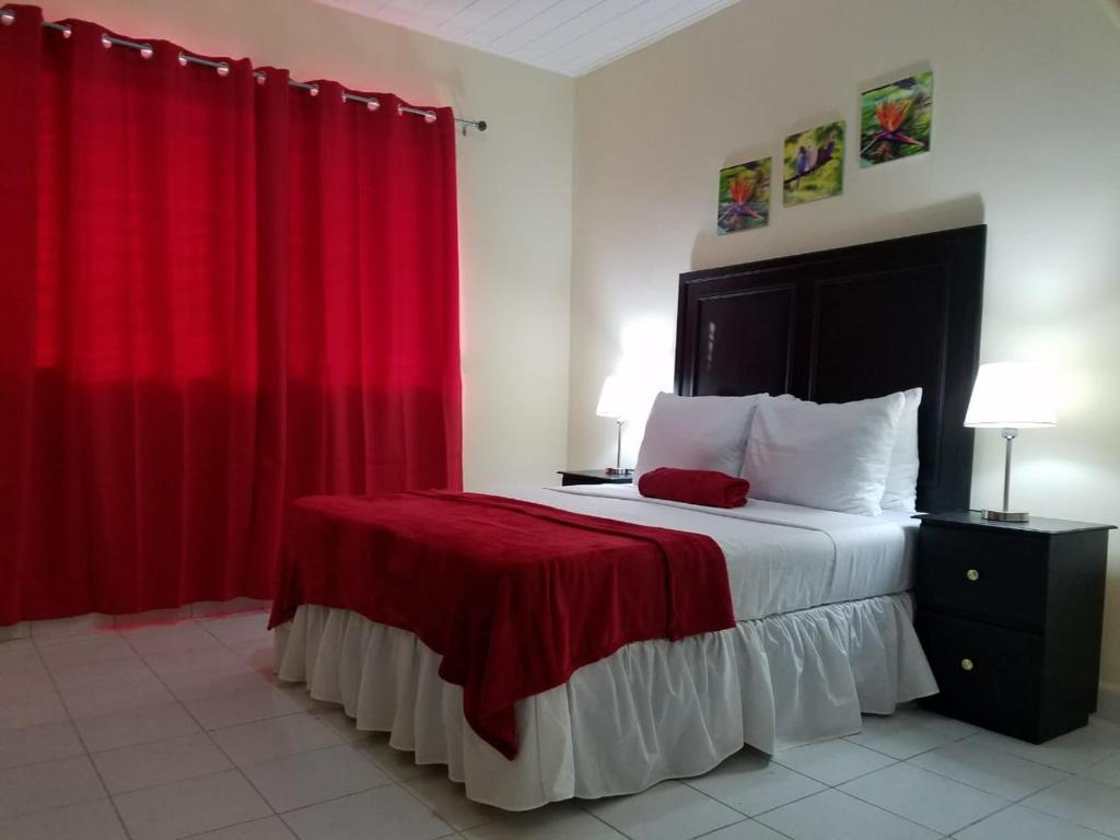 Schlafzimmer mit einem großen Bett und roten Vorhängen in der Unterkunft MH Boutique Hotel in San Pedro Sula