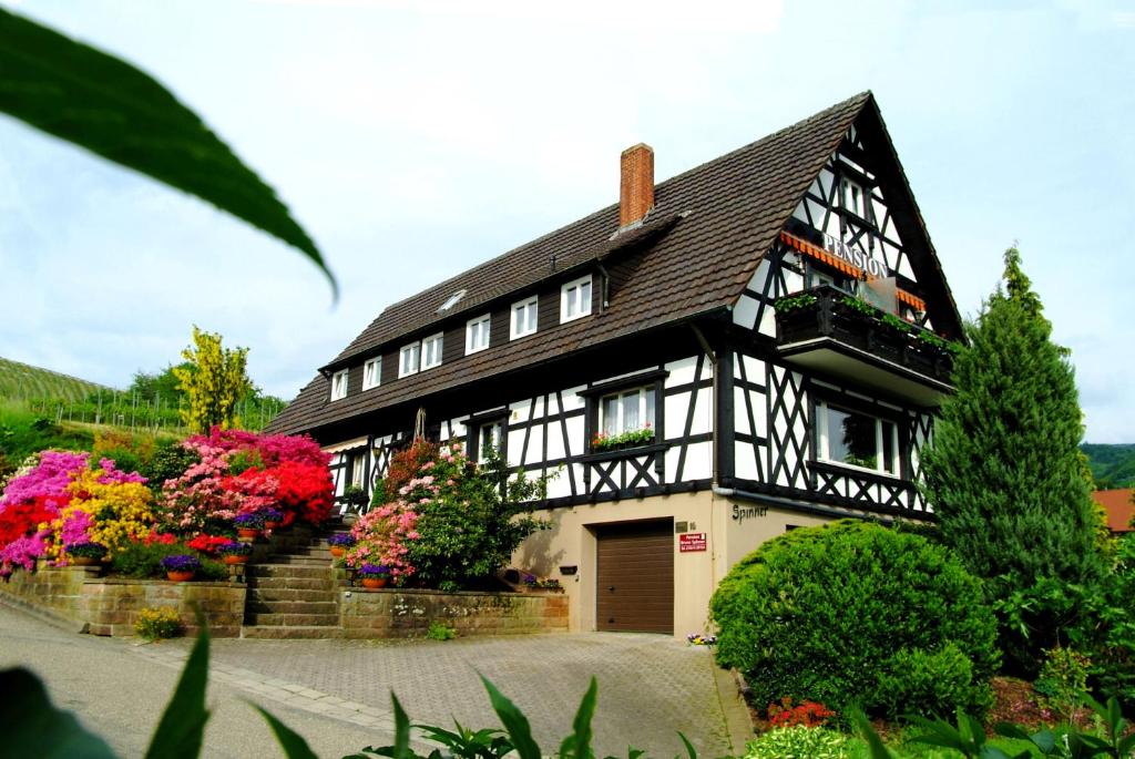 a black and white house with flowers in front of it at Pension am Weinberg in Sasbachwalden