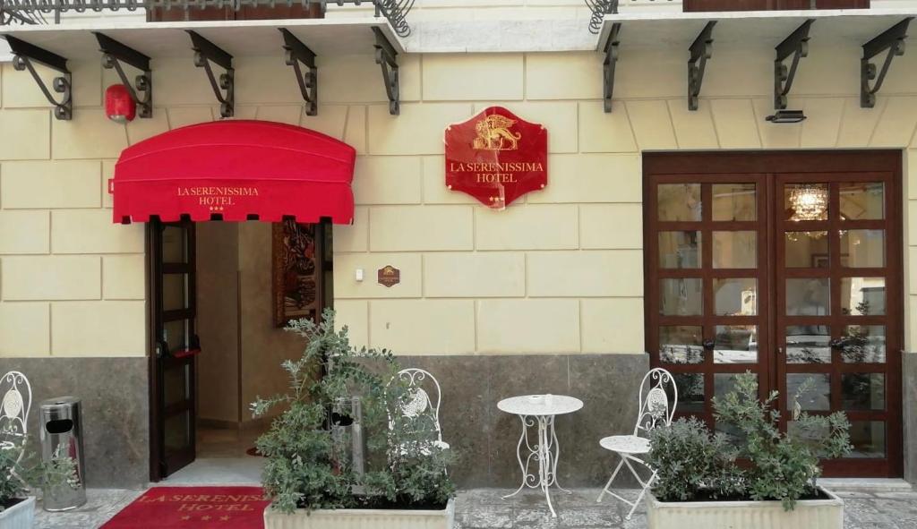 un edificio con sombrilla roja, mesa y sillas en La Serenissima Hotel, en Palermo