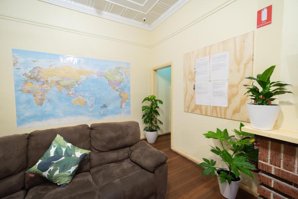 sala de estar con sofá y mapa en la pared en myOZexp Aberdeen Lodge, en Perth