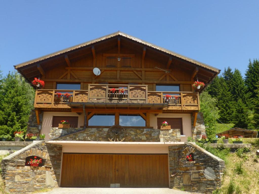 a large wooden house with a balcony and a garage at Les Saisies coté Légette appartement dans chalet LE NEPAL in Les Saisies