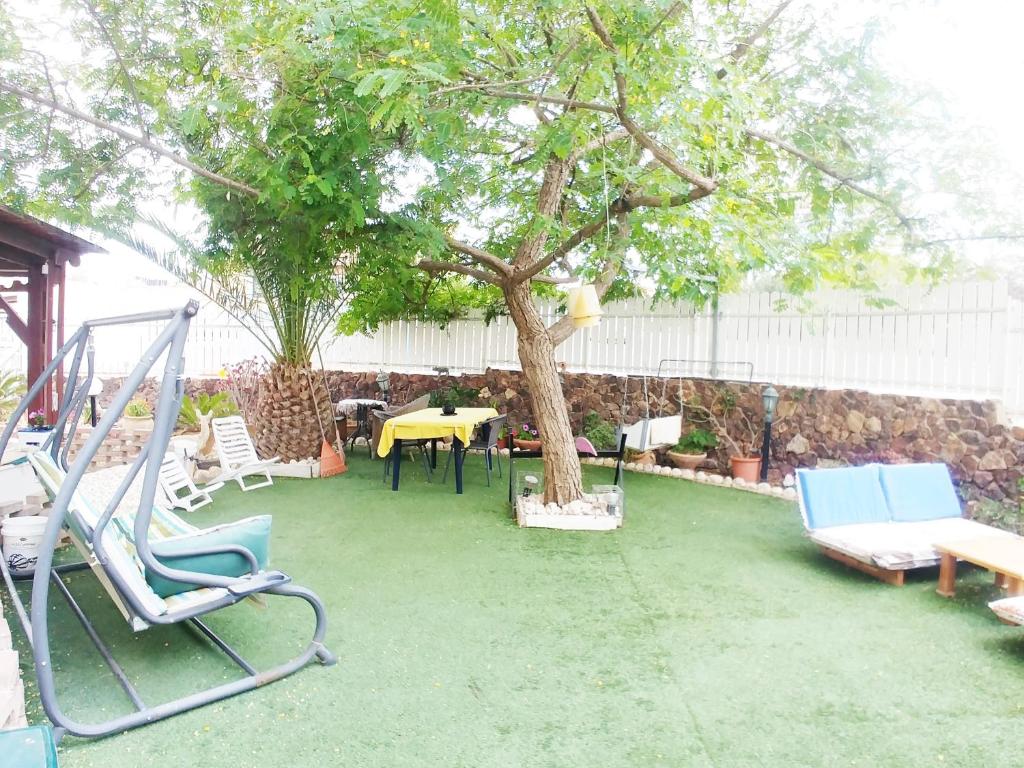 un patio con sillas, un árbol y un columpio en Carmela House, en Arad
