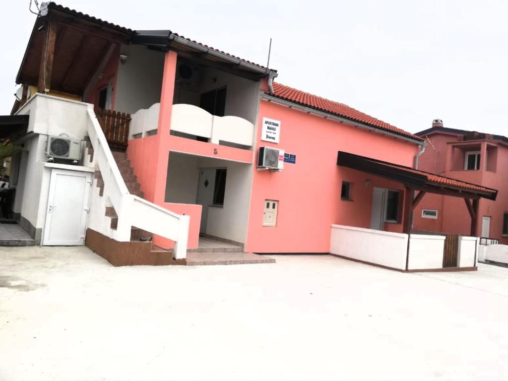 a red building with a white staircase in a parking lot at Apartments Marko in Vir