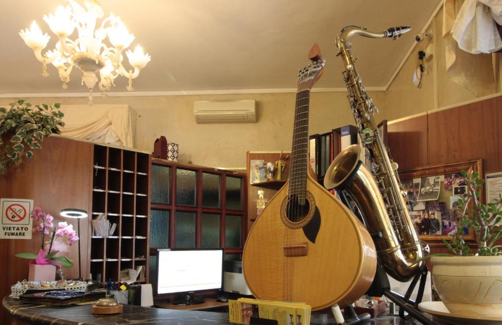 une guitare et un saxophone assis sur un bureau dans l'établissement Hotel Rose&Crown, à Correggio
