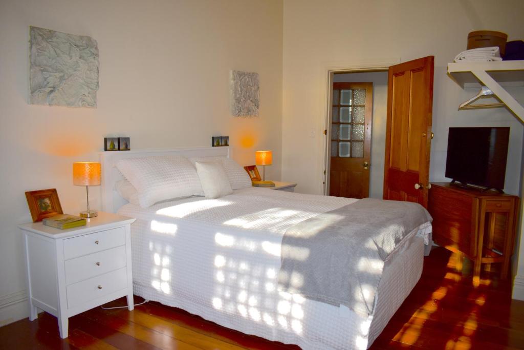 a bedroom with a white bed and a television at Prodigal Daughter Gourmet Lodge in Martinborough 