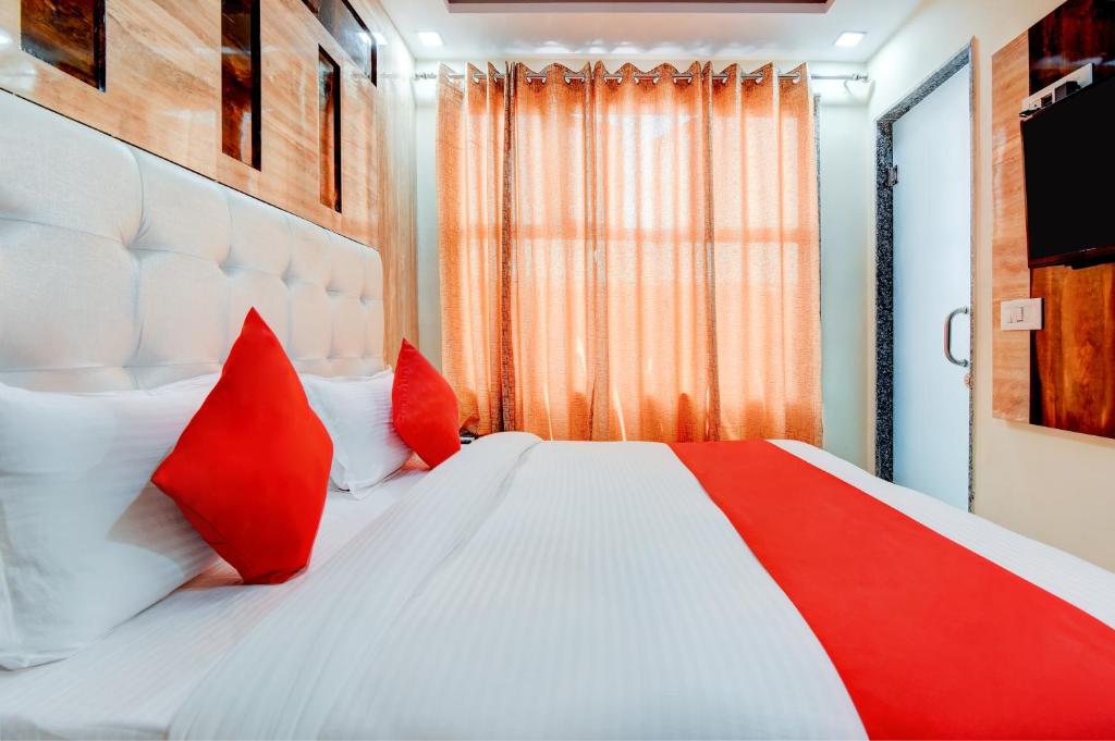 ein Schlafzimmer mit einem roten und weißen Bett mit roten Kissen in der Unterkunft Hotel Kaushal Palace in Neu-Delhi