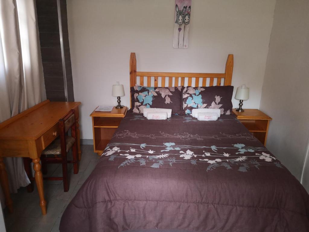 a bed in a bedroom with two night stands and a desk at Marietjies Guesthouse in Ulundi