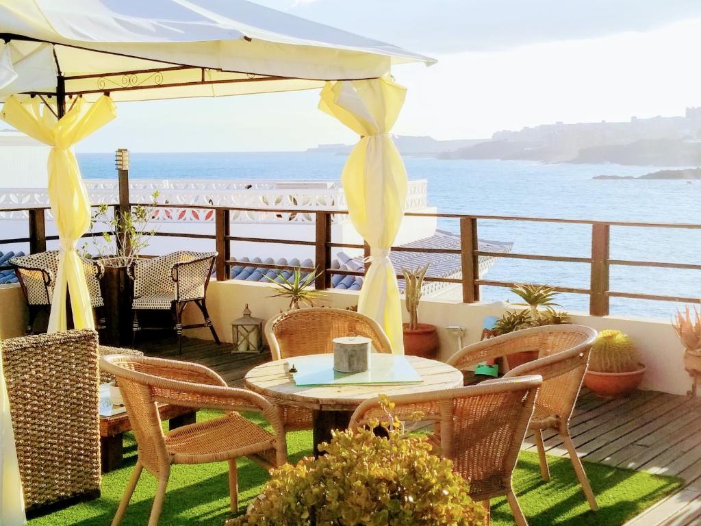 a patio with a table and chairs and the ocean at Estrella del Mar in Los Abrigos