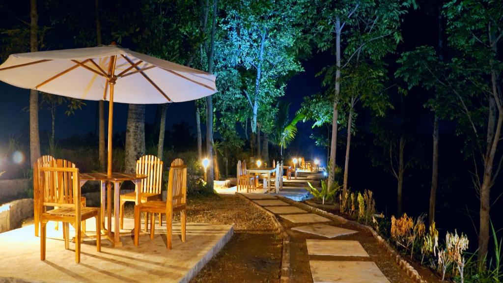 a table and chairs with an umbrella at night at Vanilla Garden in Tetebatu