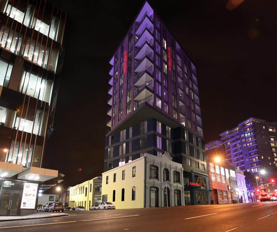 a tall building is lit up at night at Ramada Suites Victoria Street West in Auckland