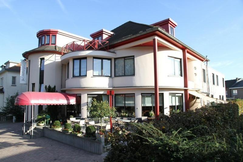 un gran edificio blanco con un restaurante frente a él en Hotel Limburgia, en Kanne