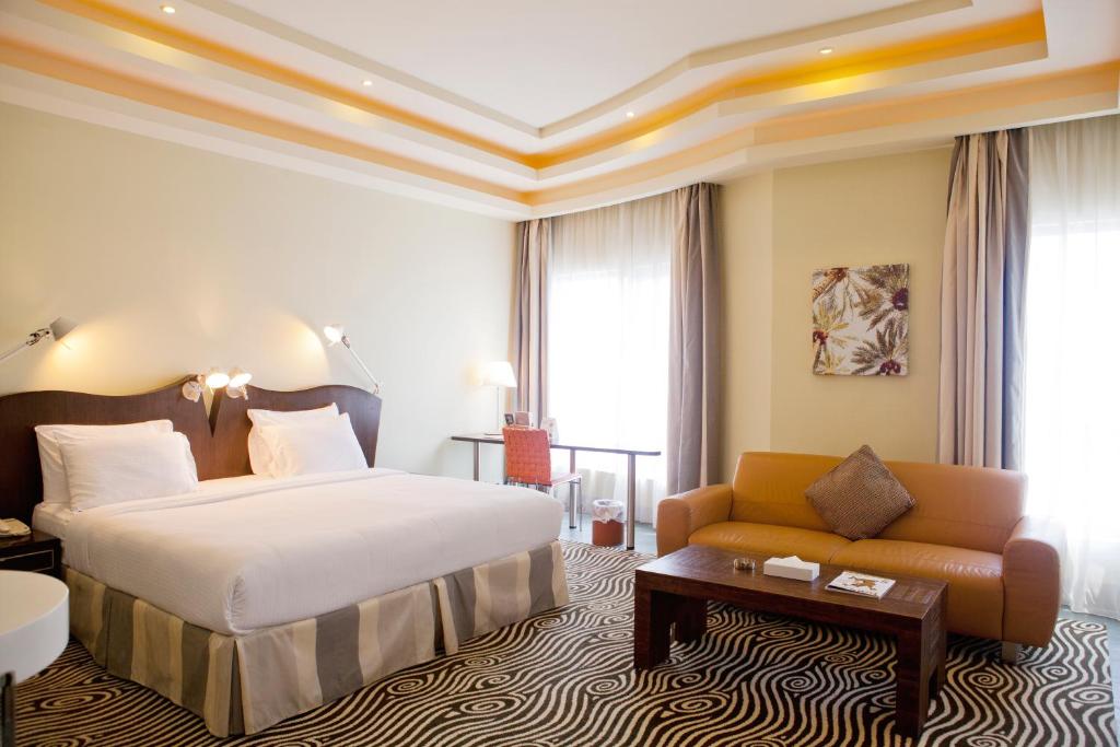 a hotel room with a bed and a couch at Al Raya Suites Hotel in Manama